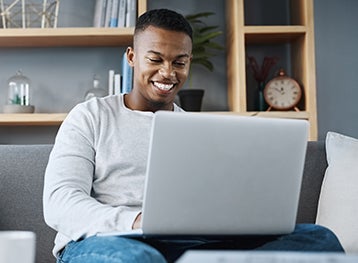 image of a man smiling at a laptop screen